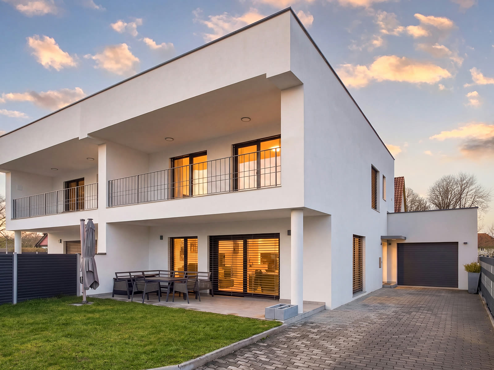 Modernes Einfamilienhaus in Abendstimmung mit warm beleuchteten Fenstern
