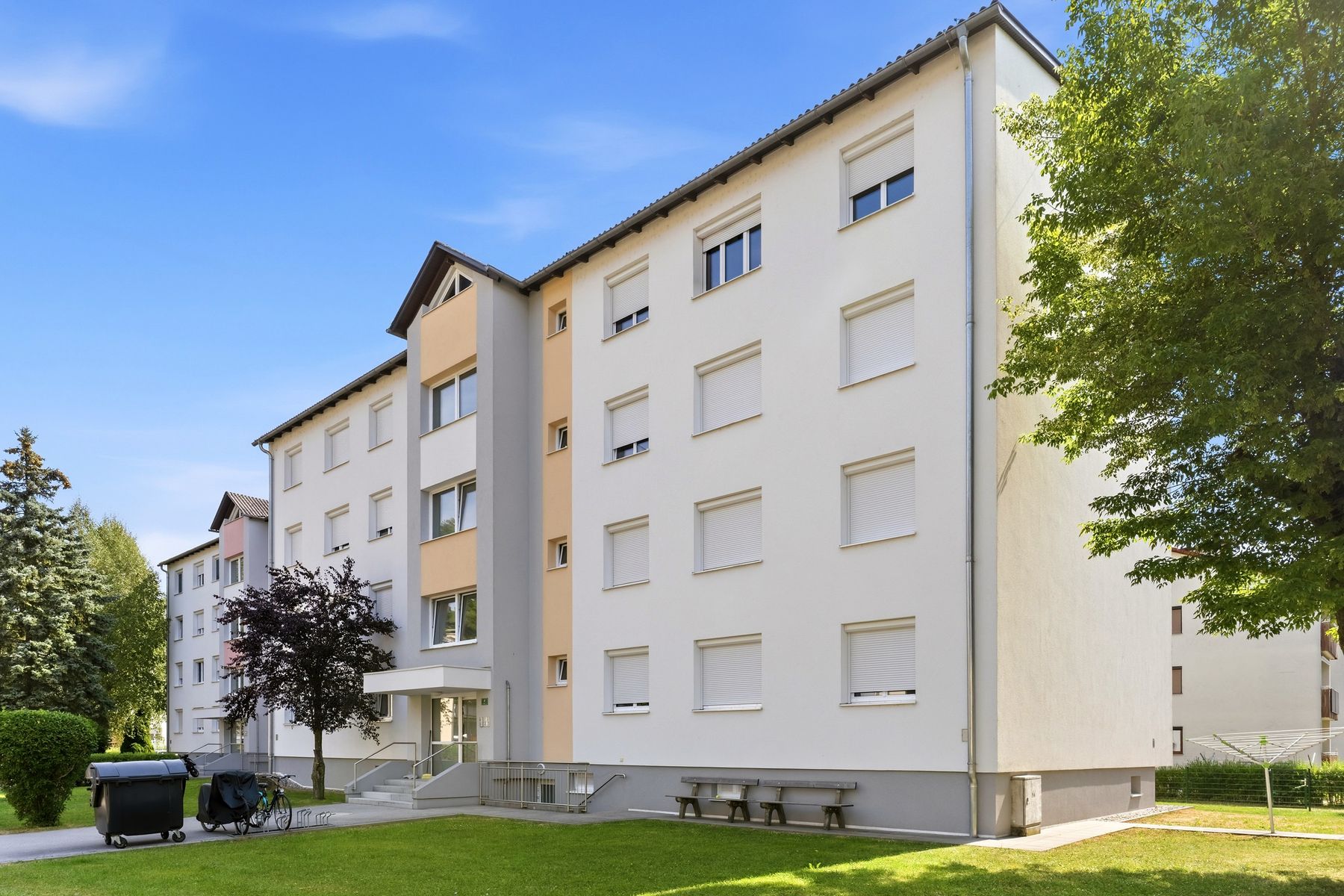 Mehrfamilienhaus mit Bäumen und Wiese