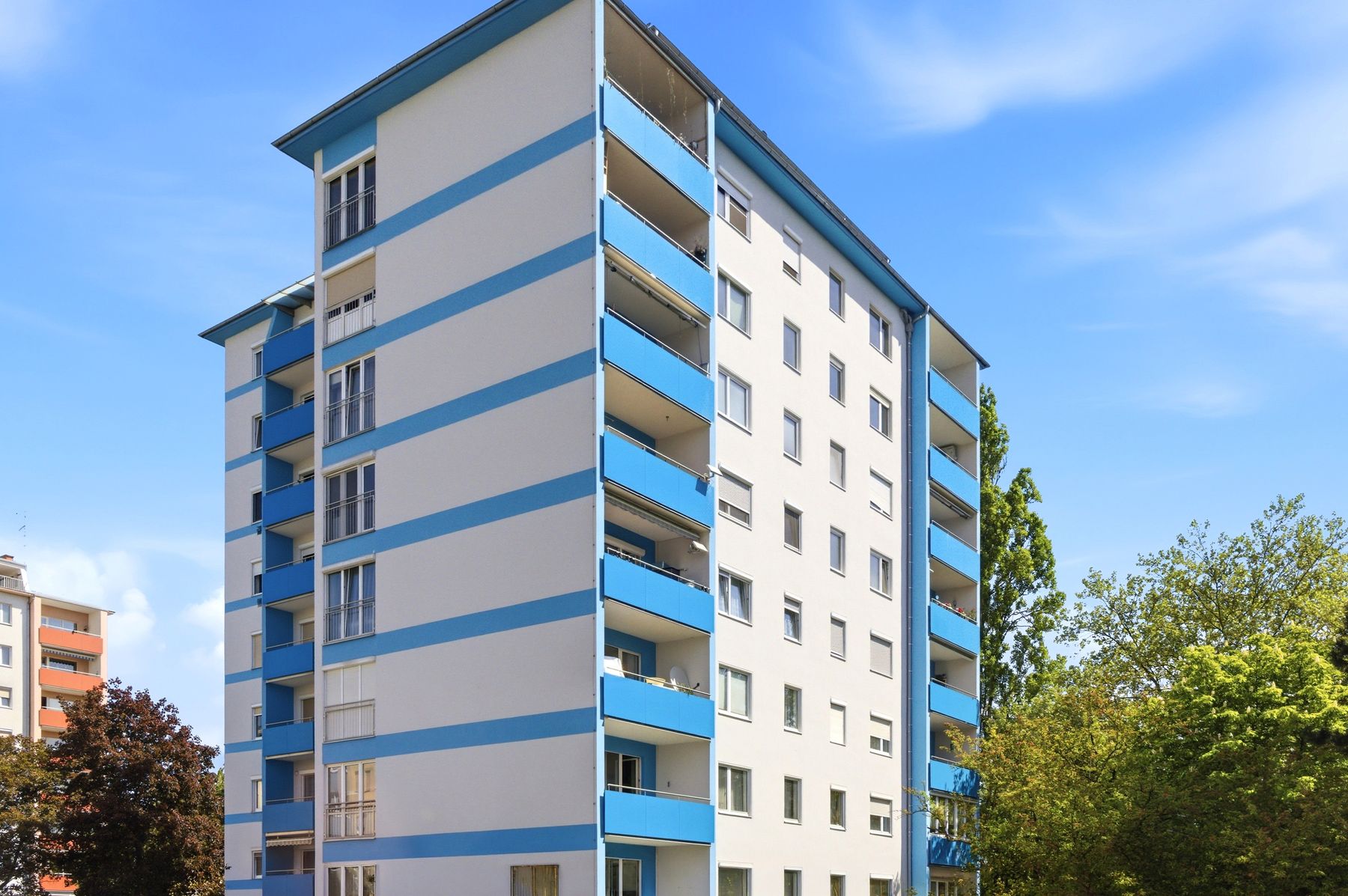 Hochhaus mit blauen Balkonen unter blauem Himmel