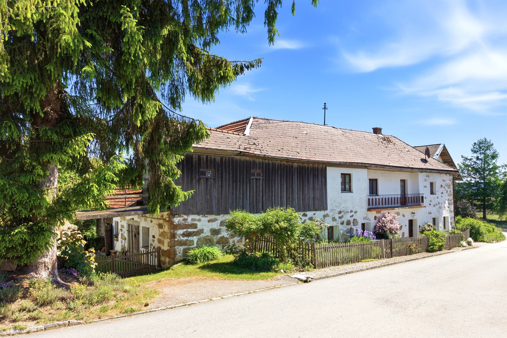Altes Steinhaus mit Holzfassade auf einer Wiese
