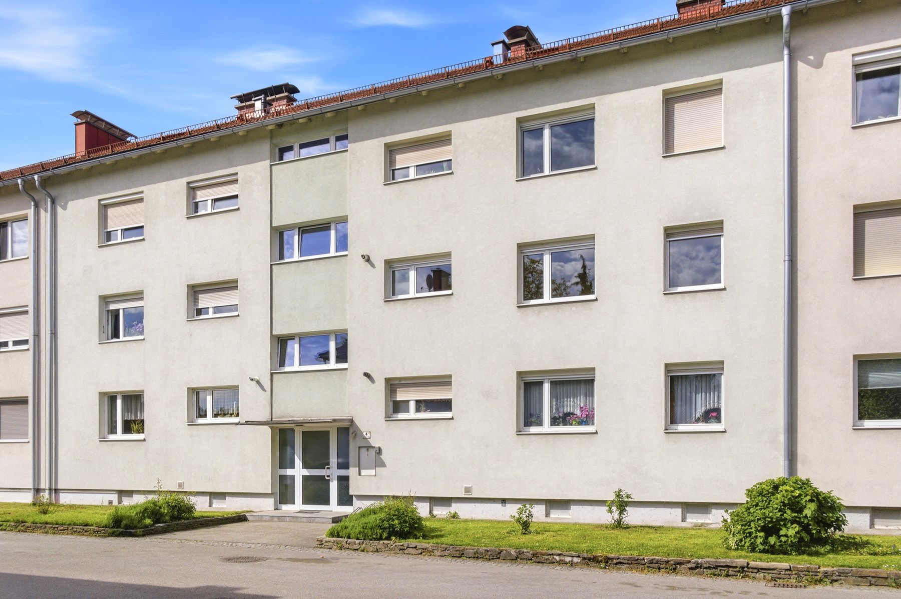Wohnblock mit hellem Putz und Bäumen