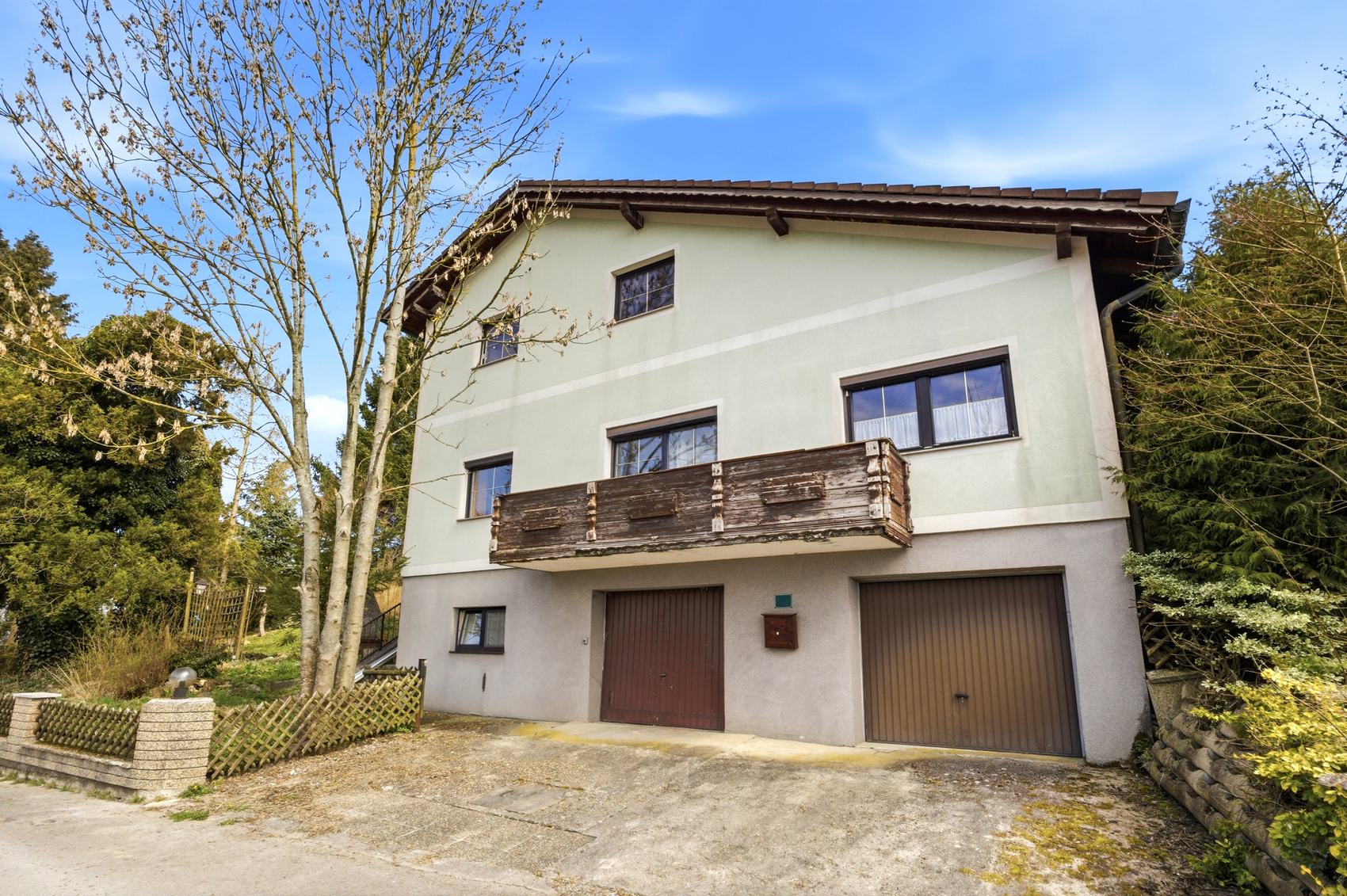 Haus mit Balkon, Garage und Bäumen