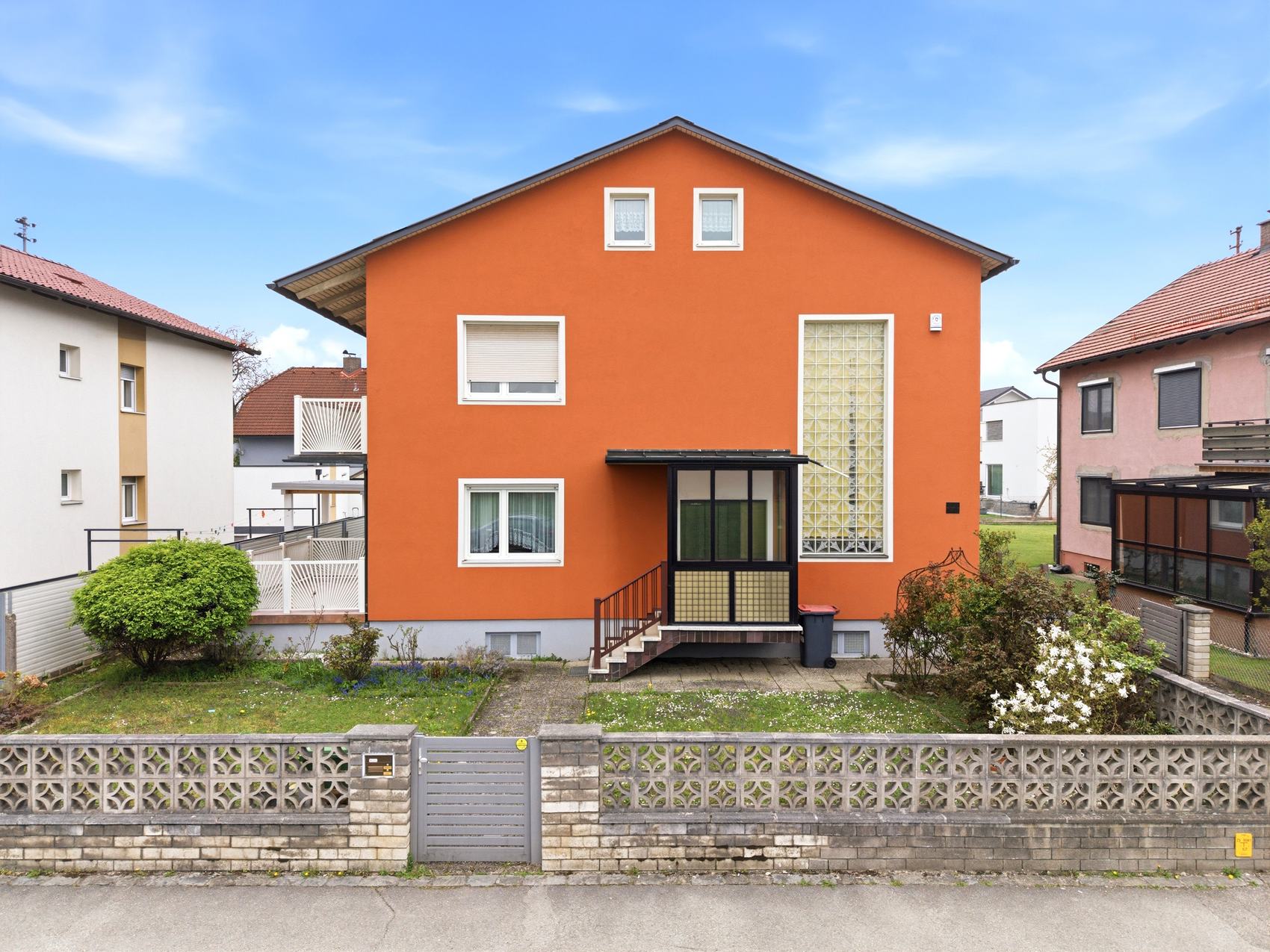 Orangefarbenes Haus mit Vorgarten und Zaun