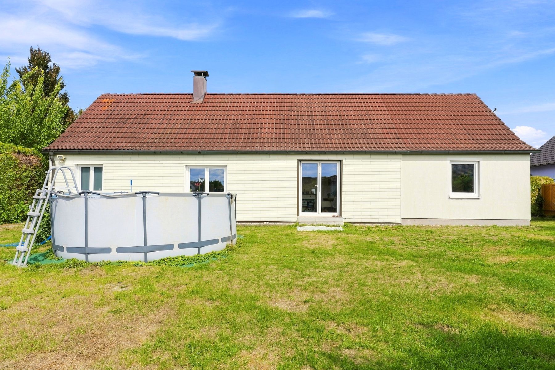 Bungalow mit rotem Dach, Rasen und Pool