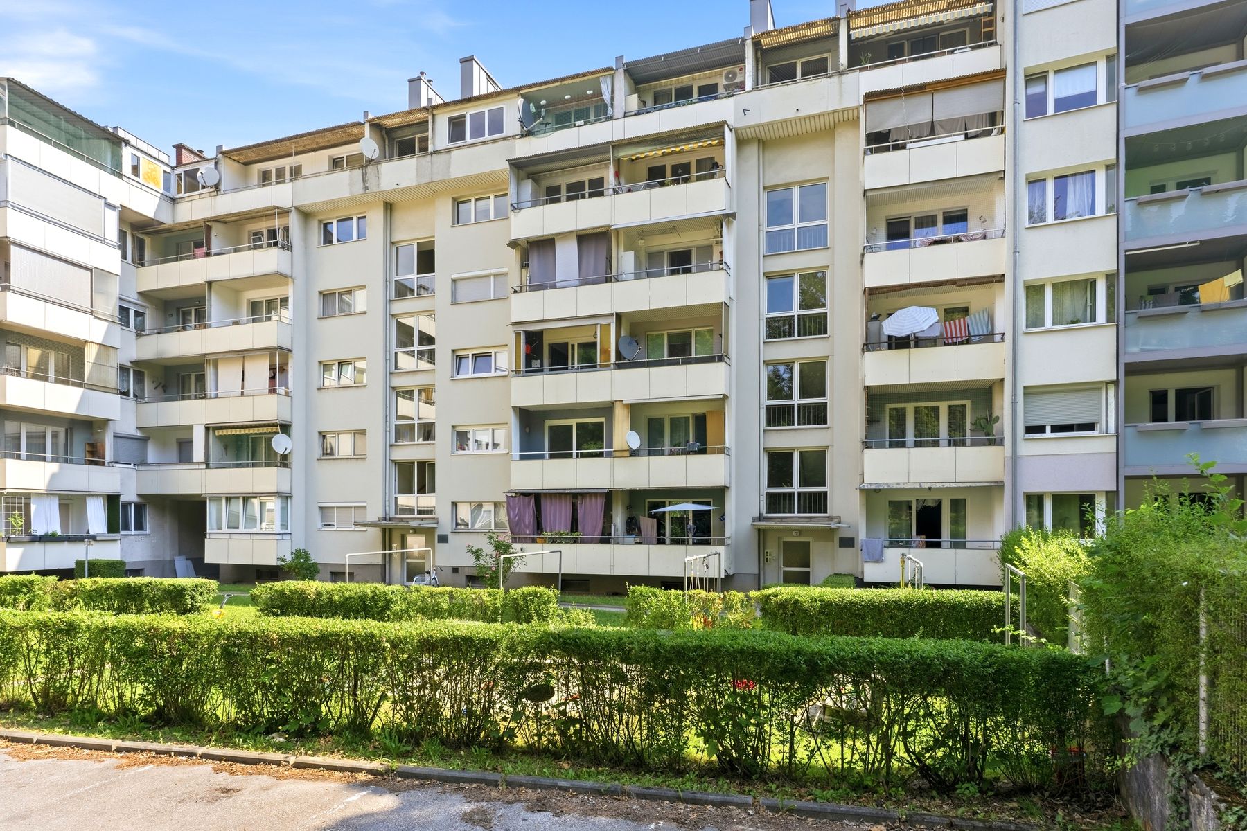 Wohnhaus mit Balkonen und Hecke